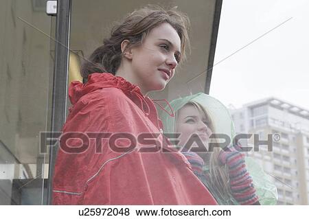 2 young women in raincoats at busstop View Large Photo Image Stock Photo - 2 young women in raincoats at busstop. Fotosearch