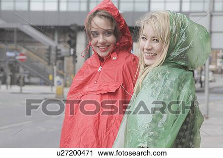 2 young women in raincoats in the city View Large Photo Image Stock Image - 2 young women in raincoats in the city. Fotosearch