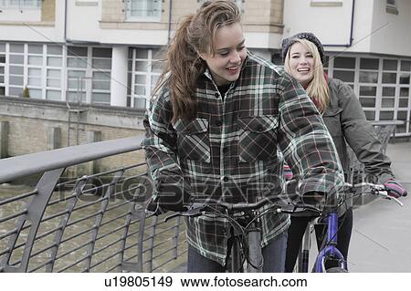 Stock Photo - 2 young women on push bikes. Fotosearch