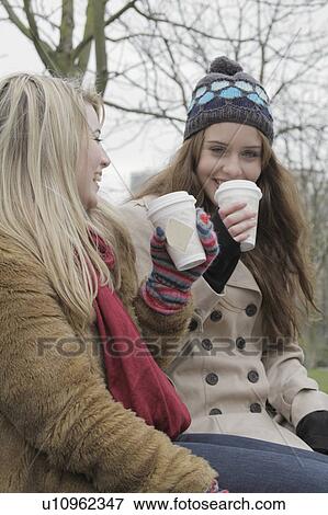 Stock Photo - 2 young women with take away cups. Fotosearch