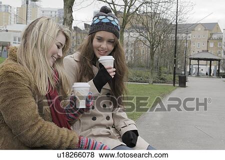 Stock Photo - 2 young women with take up cups. Fotosearch