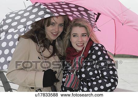 Stock Photo - 2 young women with umbrellas. Fotosearch