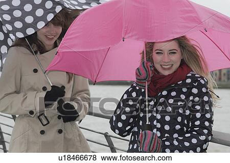 Stock Photo - 2 young women with umbrellas. Fotosearch