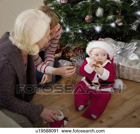 A baby dressed as Santa eating a biscuit View Large Photo Image Stock Image - A baby dressed as Santa eating a biscuit. Fotosearch