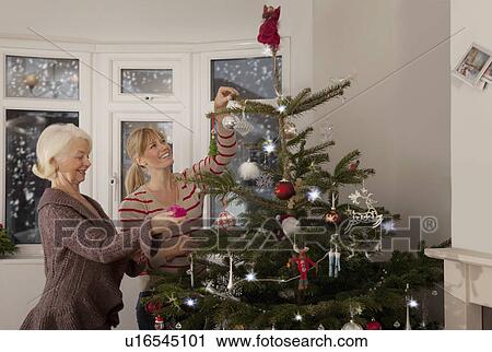Stock Image - A mother and daughter decorating a tree. Fotosearch