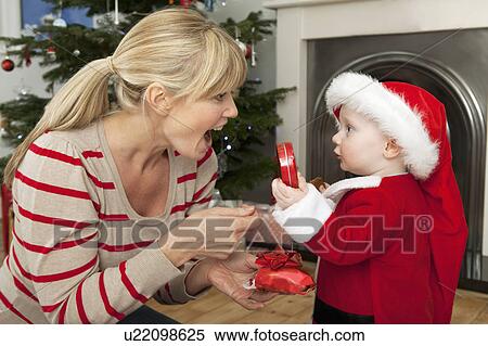 Stock Photography - A mother gives her son a Christmas gift. Fotosearch