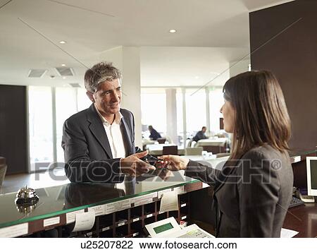 Stock Image - A Senior man receiving his Hotel Room Key. Fotosearch