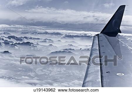 Airplane over snow covered mountains View Large Photo Image Stock Image - Airplane over snow covered mountains. Fotosearch