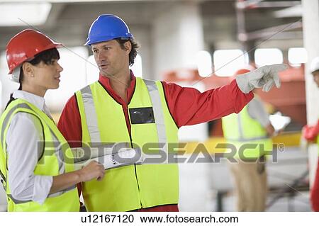 Stock Image - Architect talking to a builder. Fotosearch