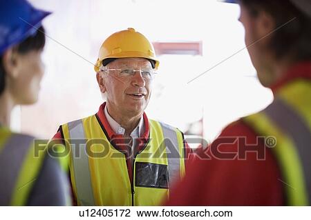 Stock Image - Architect talking to some builders. Fotosearch