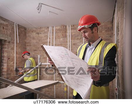 Architect with plans on building site View Large Photo Image Stock Photograph - Architect with plans on building site. Fotosearch