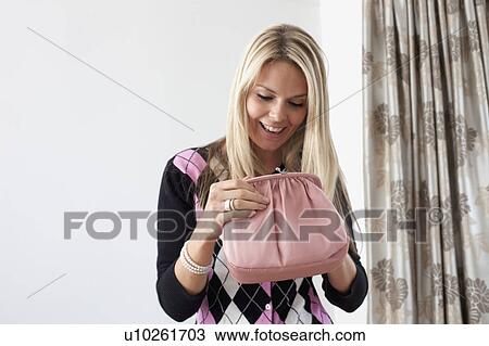 Stock Image - Attractive blond woman looking in purse. Fotosearch