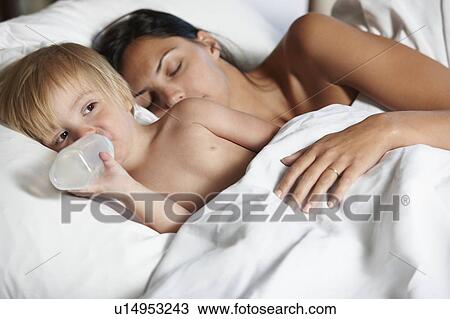 Baby boy drinking bottle in bed with mom View Large Photo Image Stock Image - Baby boy drinking bottle in bed with mom. Fotosearch