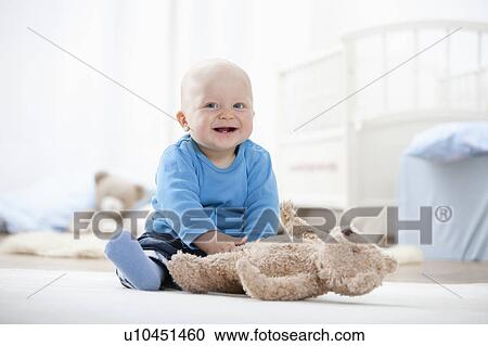 Stock Image - Baby boy playing with teddy bear. Fotosearch