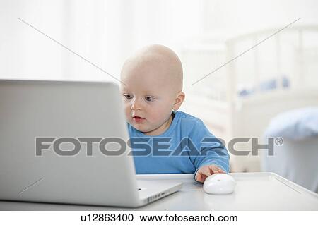Stock Image - Baby boy using laptop. Fotosearch