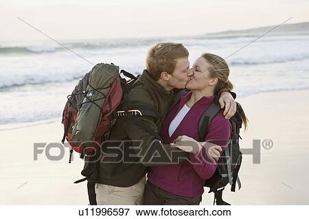 Stock Photo - Backpacking couple kissing at beach. Fotosearch