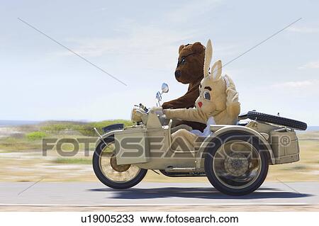 Stock Image - Bear and bunny riding a motorbike. Fotosearch