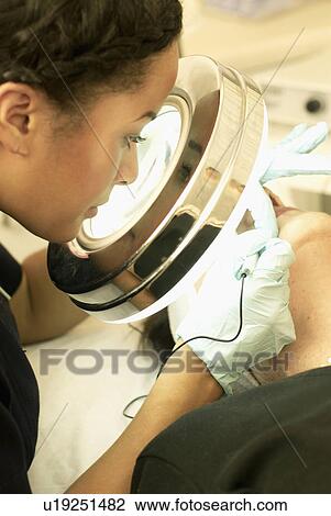 Stock Image - Beautician performing epilation. Fotosearch