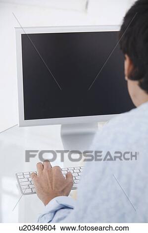 Picture - Blank computer screen, shot from over a mans shoulder. Fotosearch
