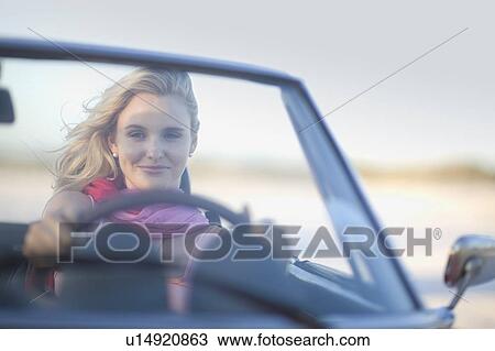 Stock Image - Blond girl driving a cabriolet. Fotosearch