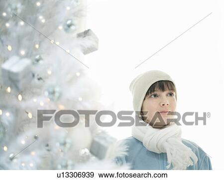 Boy (8-10) standing by lit Xmas tree View Large Photo Image Stock Photo - Boy (8-10) standing by lit Xmas tree. Fotosearch