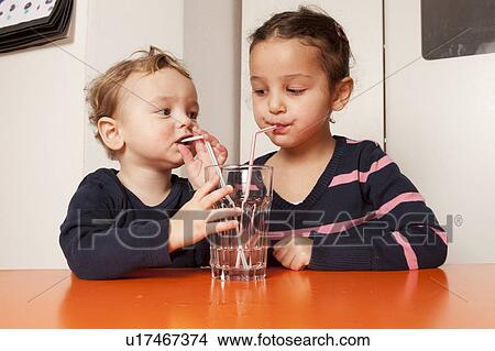 Picture - Boy and girl drinking water with straws. Fotosearch