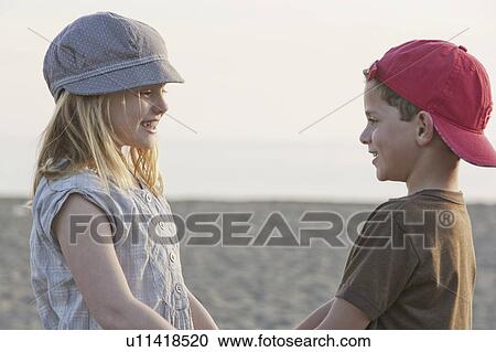 Stock Image - Boy and girl holding hands at beach. Fotosearch