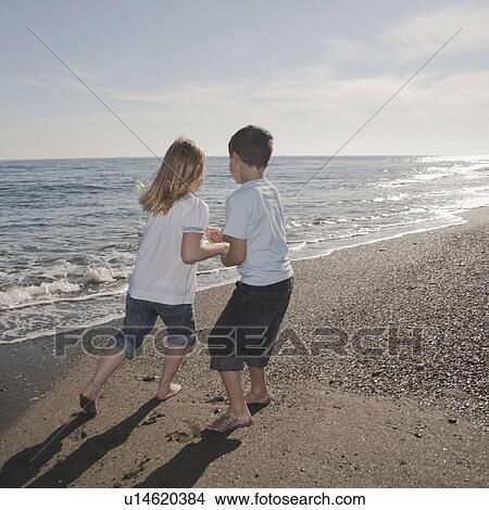 Picture - Boy and girl running on beach. Fotosearch