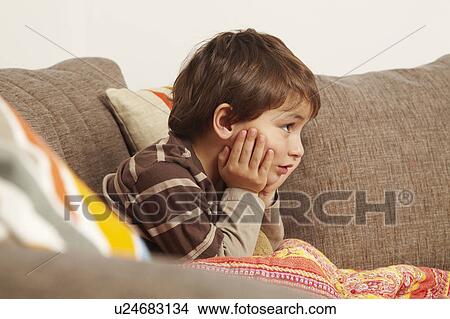 Picture - Boy on sofa staring at television. Fotosearch