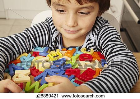 Stock Image - Boy playing with letters in kitchen. Fotosearch
