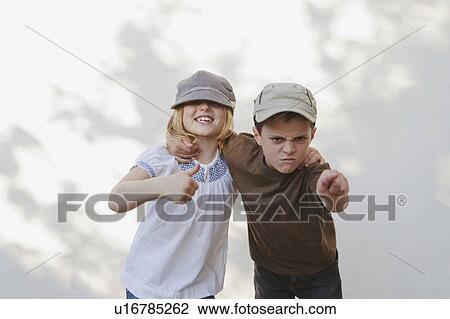 Stock Image - Boy pointing with girl giving thumbs up. Fotosearch