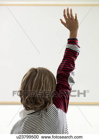 Stock Image - Boy raising hand in classroom. Fotosearch