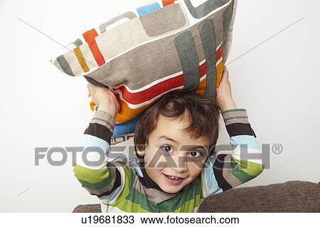 Stock Image - Boy throwing cushion. Fotosearch