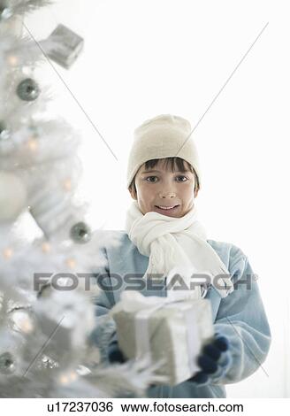 Stock Photograph - Boy with present by Xmas tree. Fotosearch