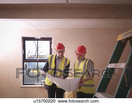Stock Image - Builder and architect with plans. Fotosearch
