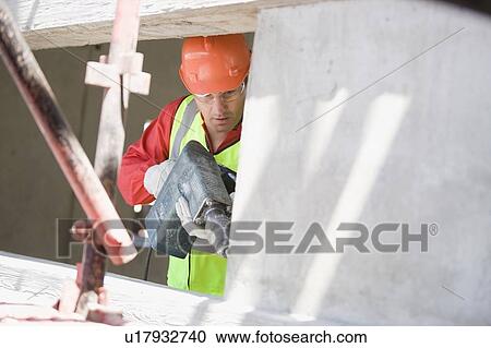 Stock Image - Building worker handling a drill. Fotosearch