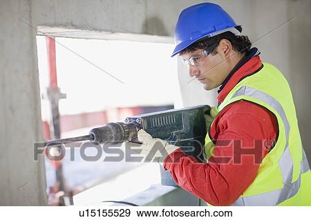 Building worker handling a power drill View Large Photo Image Stock Photo - Building worker handling a power drill. Fotosearch