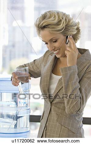 Stock Image - Buisness woman on the phone with water. Fotosearch