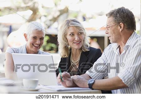 Stock Image - Business people using laptop outdoors. Fotosearch