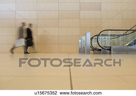 Business people walking towards an escalator View Large Photo Image Stock Image - Business people walking towards an escalator. Fotosearch