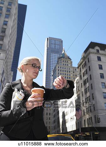 Stock Photo - Business woman looking at her watch. Fotosearch