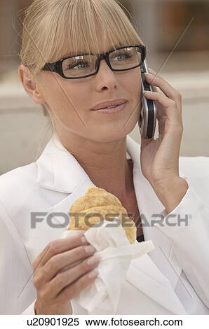 Stock Photography - Business woman on the phone with pastry. Fotosearch