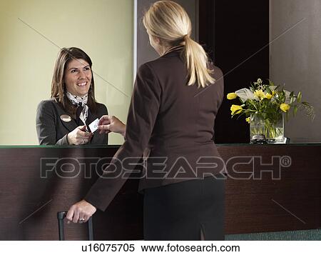 Stock Photography - Business woman paying for her hotel room at front desk. Fotosearch