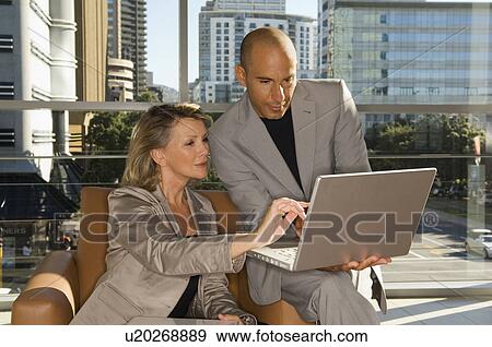 Businessman and woman looking at laptop View Large Photo Image Stock Photo - Businessman and woman looking at laptop. Fotosearch