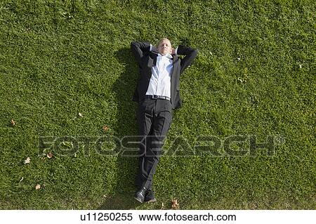 Stock Photography - Businessman laying in grass. Fotosearch