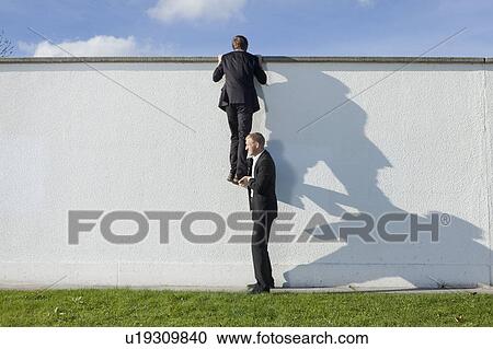 Businessman lifting colleague over wall View Large Photo Image Stock Image - Businessman lifting colleague over wall. Fotosearch