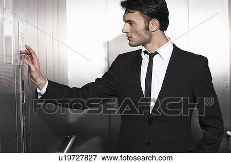 Stock Photo - Businessman pressing elevator buttons. Fotosearch