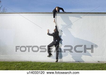 Businessman pulling colleague over wall View Large Photo Image Stock Image - Businessman pulling colleague over wall. Fotosearch
