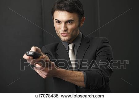Stock Photograph - Businessman using remote control. Fotosearch