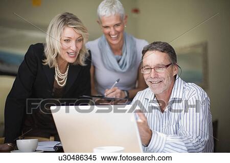 Stock Photography - Businesspeople using laptop together. Fotosearch